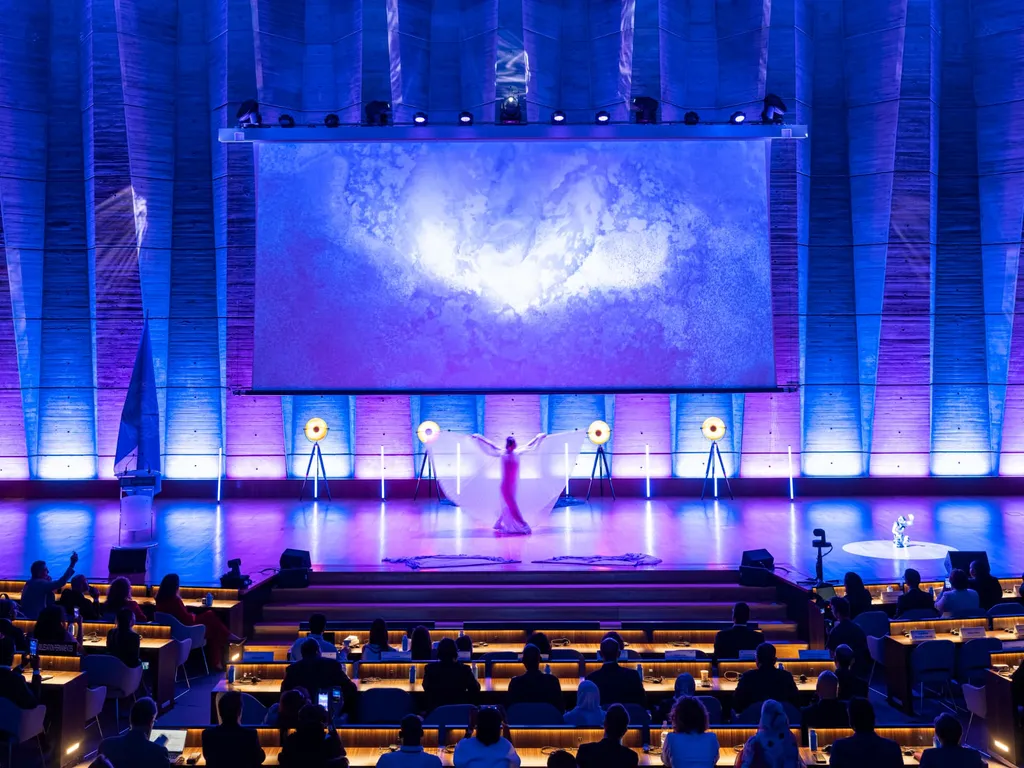 Voiles roses déployés sous la lumière rouge, en dialogue avec le robot sur scène.